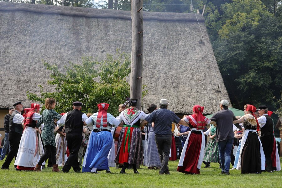 Historische Trachtenaufführung der Öwerpetters, Foto: Klaus Mayhack eine tanzende Trachtengruppe auf dem Außengelände des Freilichtmuseums vor einem Reetdachhaus