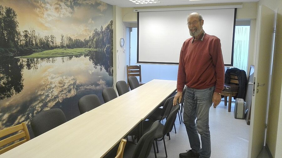 Ein Mann steht in einem Seminarraum an einem langen Tisch