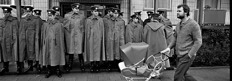 Mann mit Kinderwagen vor Volkspolizisten auf der Karl-Marx-Allee in Ost-Berlin 1978, Foto: Harald Schmitt Mann mit Kinderwagen vor Volkspolizisten auf der Karl-Marx-Allee in Ost-Berlin 1978