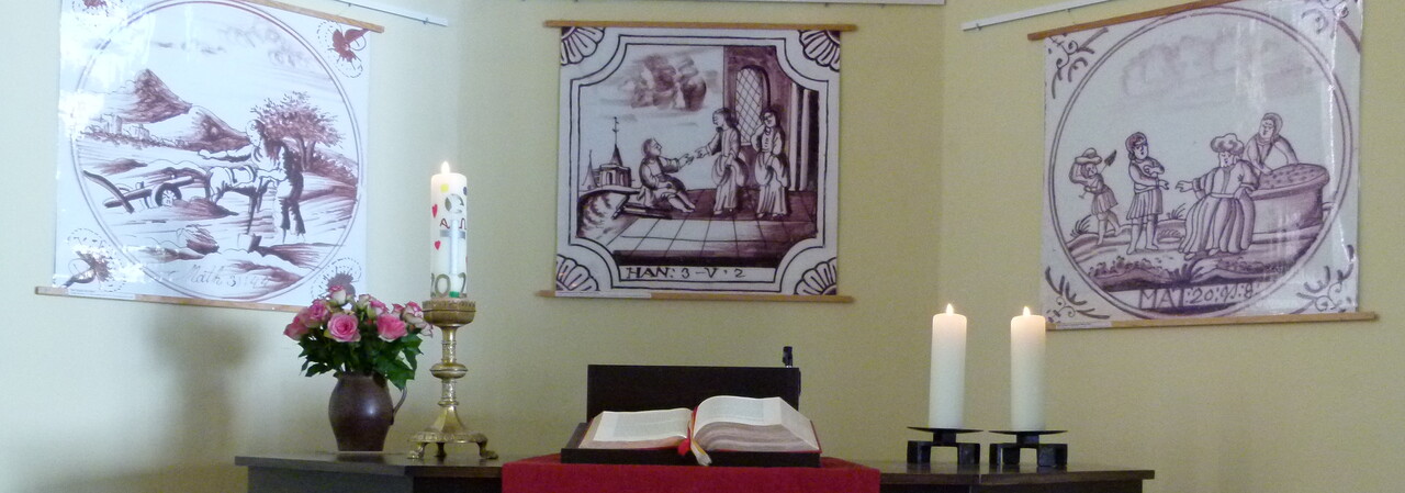 Altar, hinter dem drei Poster mit darauf abgebildeten Bibelfliesen hängen