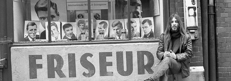 Mann sitzt vor Friseurladen auf St. Pauli, 1964