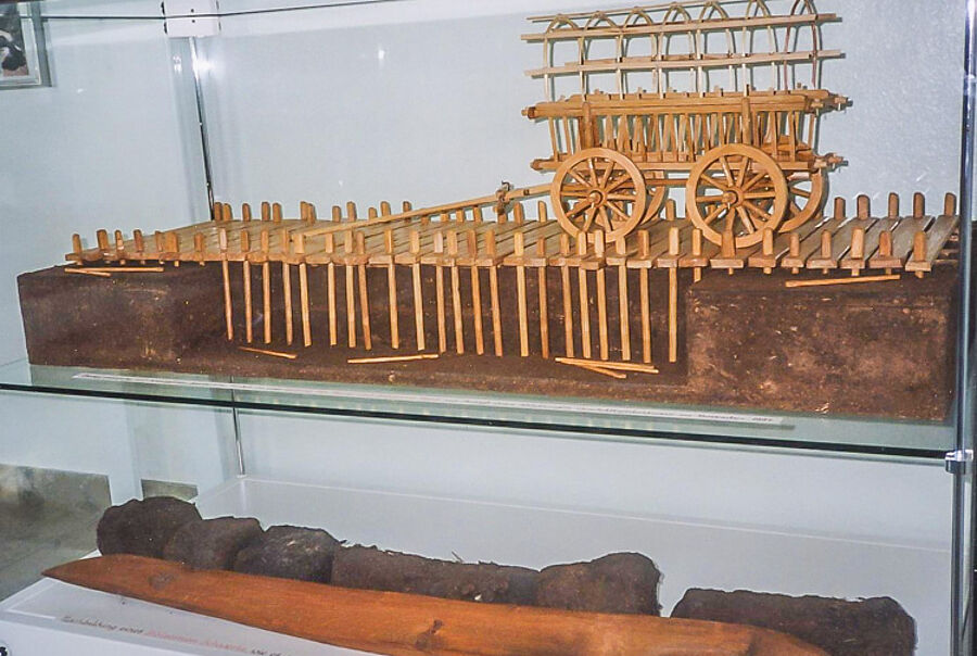 Modell eines im Dammer Moor ausgegrabenen Bohl- und Pfahlweges mit Holzschwert-Nachbau unten, 200/300 v. Chr.