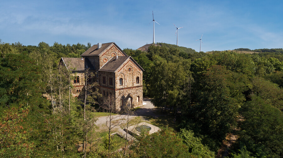 Haseschachtgebäude mit Windrädern - Außenaufnahme umgeben von Wald