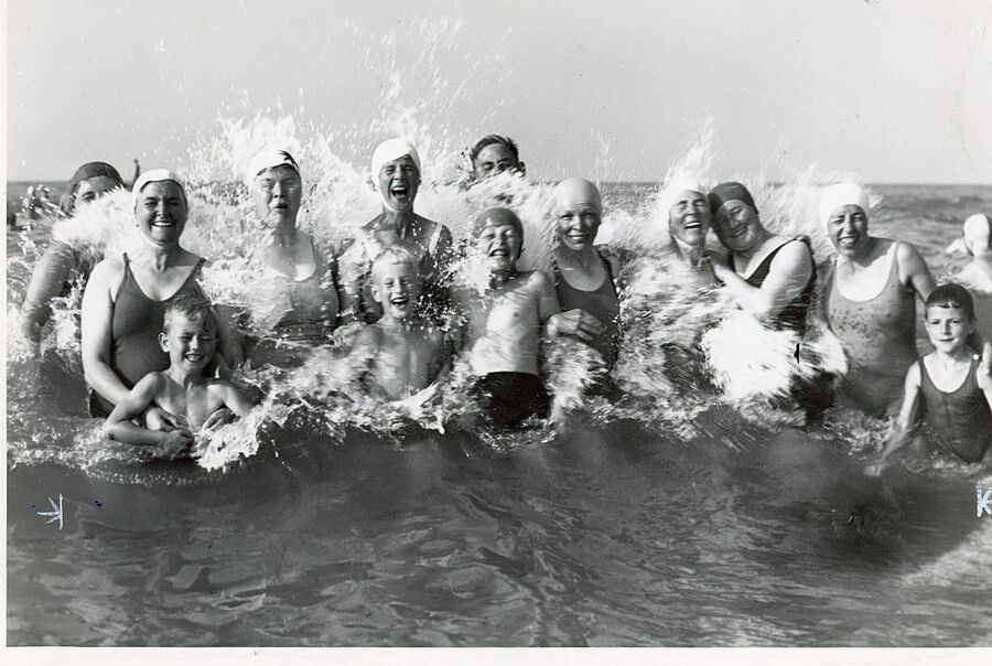 Schwarz-weiß-Foto mit Menschen, die in der Brandung baden