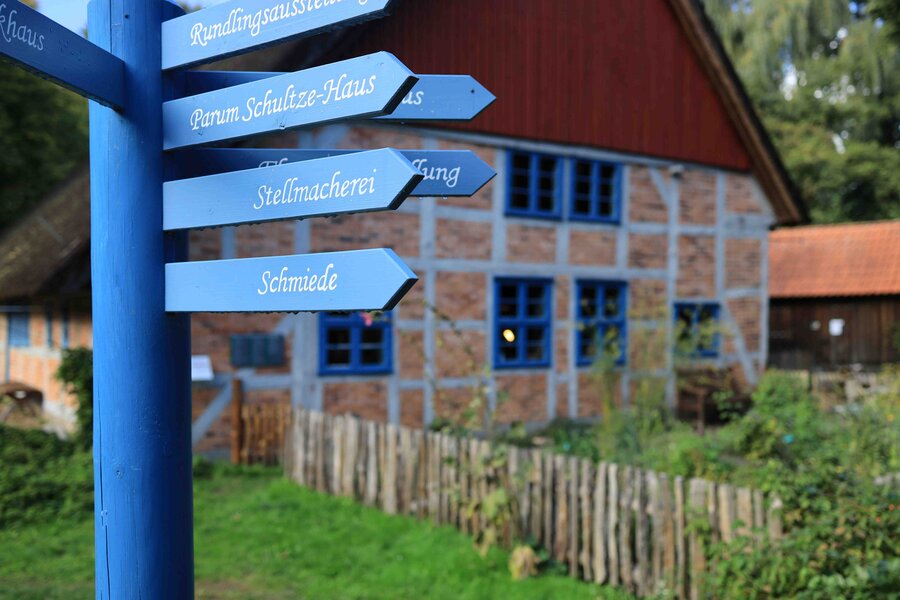 Außengelände Rundlingsmuseum Wendland, Foto: Klaus Mayhack Außengelände des Freilichtmuseums, das Bild zeigt einen blauen Wegweiser vor einem Fachwerkhaus