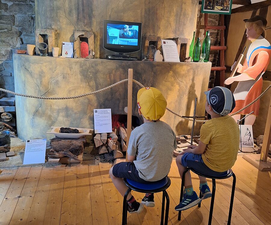 In der historischen Waldglasausstellung, zwei Kinder sitzen vor einem Bildschirm